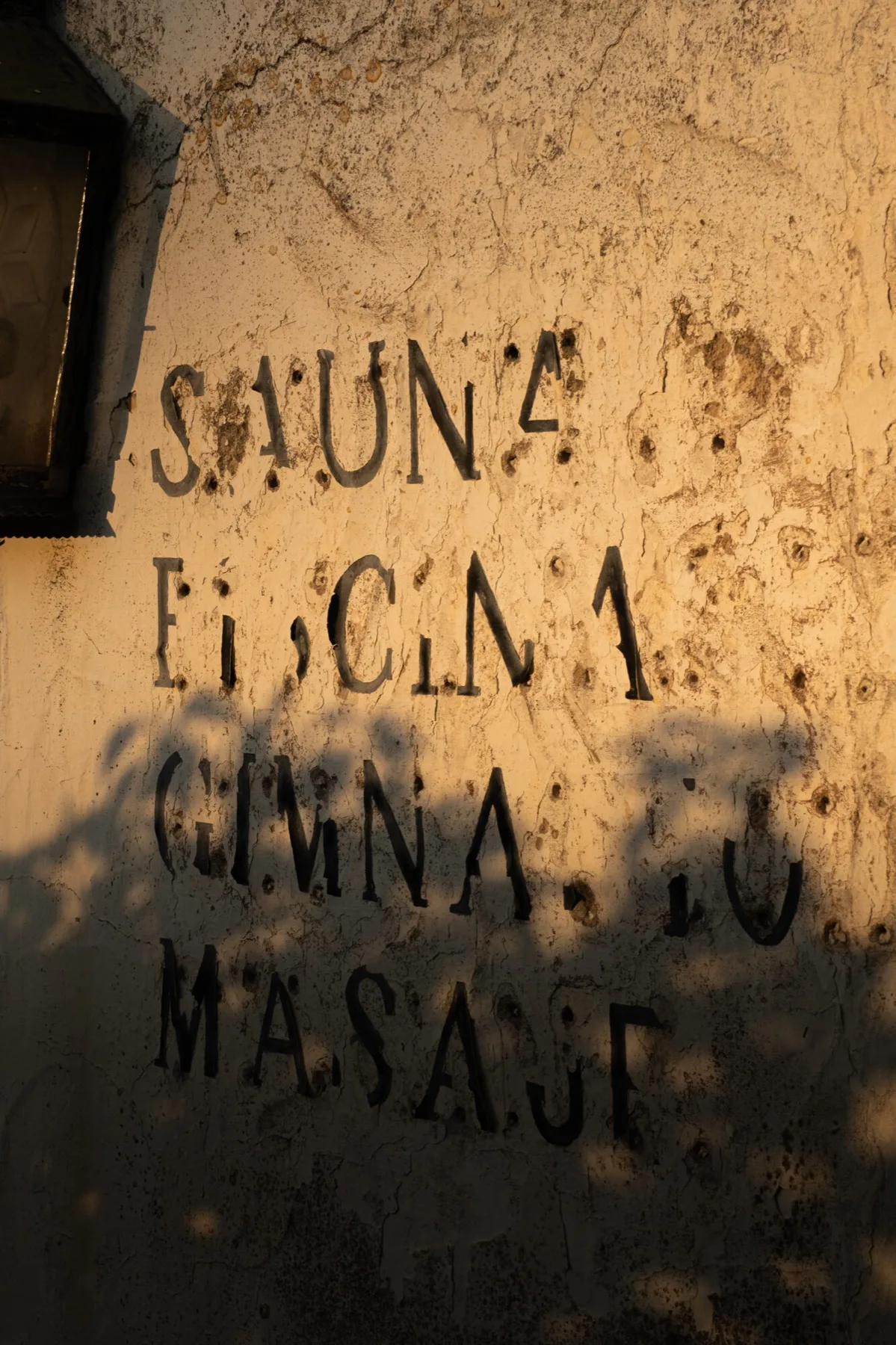 Sauna, Piscina, Gimnasio, Masaje — stencilled on a wall